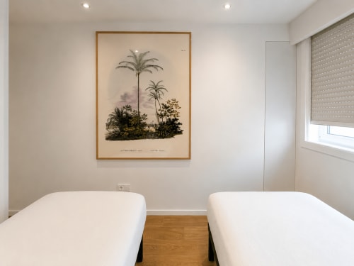 Camas gemelas en apartamento moderno de Baiona con estampado botánico de palmas, piso de madera y decoración minimalista