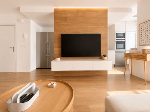Sala de estar moderna en Baiona con suelos de madera, pared de TV, muebles blancos y electrodomésticos de acero inoxidable
