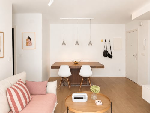 Moderna sala de estar en Baiona con mesa de comedor, luces colgantes blancas y sofá rosa con cojines rayados