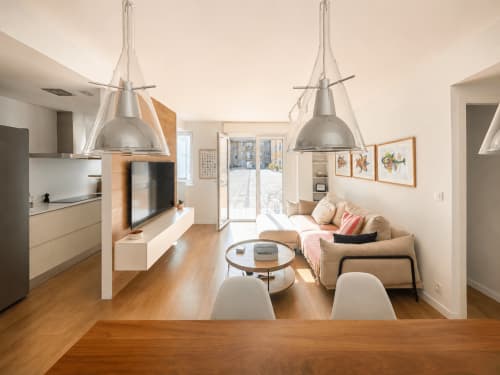 Moderno apartamento de planta abierta en Baiona con cocina, sala de estar, luces colgantes, sofá beige, televisor y suelo de madera