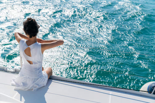 Mujer con vestido blanco en yate admirando el mar Mediterráneo turquesa cerca de Fuengirola