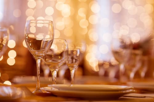 Elegante tavolo con calici di vino e piatto al Ponteronico Resort di Sessa Aurunca, illuminato da calde luci sfocate