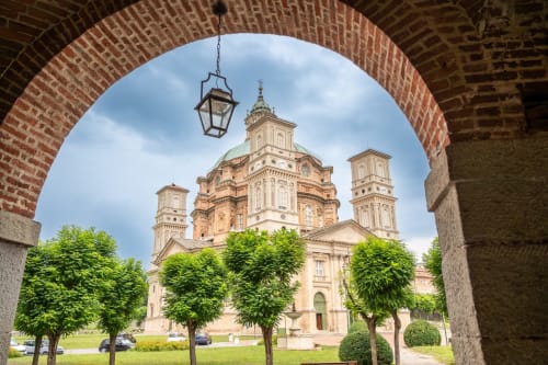 Chiesa barocca con cupola dorata incorniciata da arco in laterizio, Ceva CN Italia