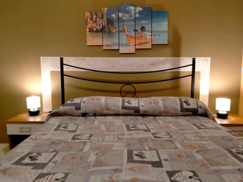 Camera moderna di Villa Laura B&B a Giardini Naxos con opere d'arte marina, letto in ferro battuto nero e illuminazione ambient