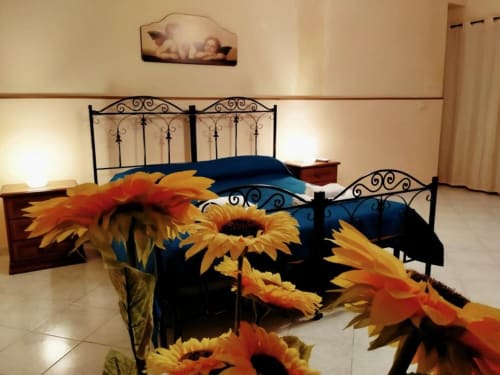 Camera da letto di Villa Laura B&B Giardini Naxos con decorazione girasole e letto in ferro battuto