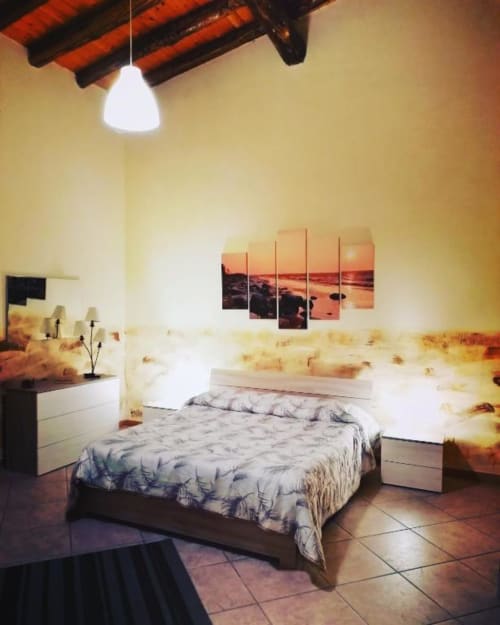 Camera da letto di Villa Laura B&B a Giardini Naxos con letto matrimoniale, comodini bianchi, opera tramonto e lampada a sospensione