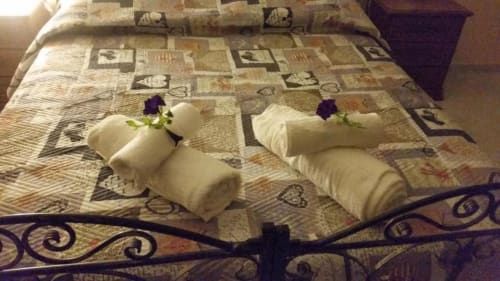 Due letti gemelli con asciugamani arrotolati e fiori a Villa Laura B&B a Giardini Naxos, Sicilia