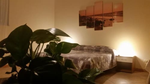 Camera tripla di Villa Laura B&B a Giardini Naxos con letto, pianta verde, TV e quadro paesaggio tramonto
