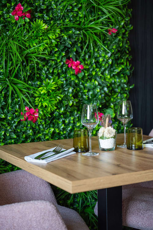 Elegant dining table at Hôtel Restaurant Le S'Y with wine glasses, fresh flowers, and lush green wall backdrop