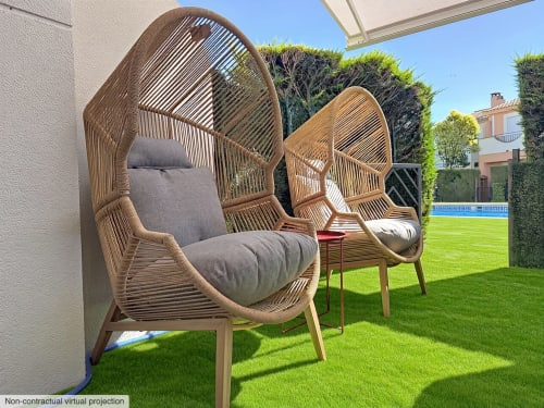 Deux fauteuils oeuf tissés avec coussins gris sur pelouse verte à la location Estartit avec vue sur piscine