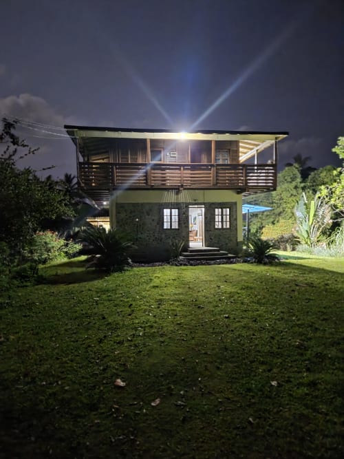 Casarão Equador Vila Paraíso quarto duplo à noite em São Tomé, com deck superior iluminado com corrimão e piso térreo