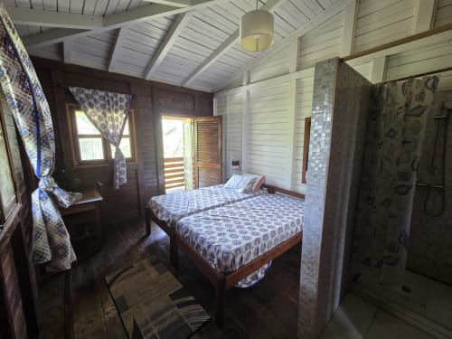 Espaçoso quarto duplo na Vila Paraíso, Casarões de São Tomé, com camas de madeira e acesso a varanda com vista para o mar