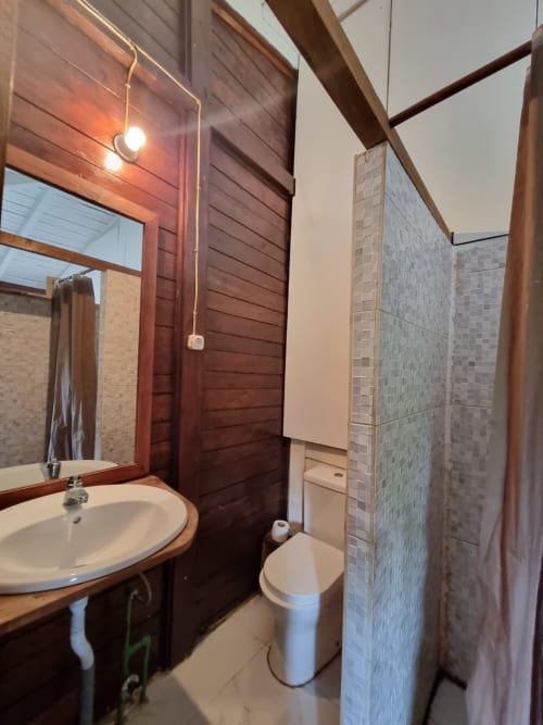 Banheiro moderno na suite Vila Paraíso da Equador Houses, São Tomé, com acabamentos em madeira, cuba redonda e piso em azulejos
