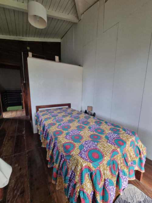 Colcha colorida com padrões em cama de madeira em quarto claro na Vila Paraíso, Casarões de Equador, São Tomé