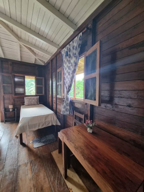 Quarto aconchegante em madeira em Vila Paraíso, São Tomé, com cama de casal, vista para o mar e charme rústico