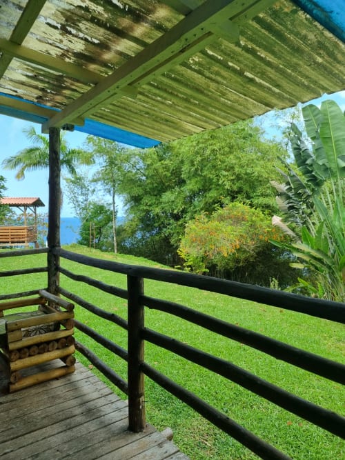 Plataforma de madeira com corrimão preto com vista para o exuberante jardim verde e oceano azul nas Casas do Equador, São Tomé