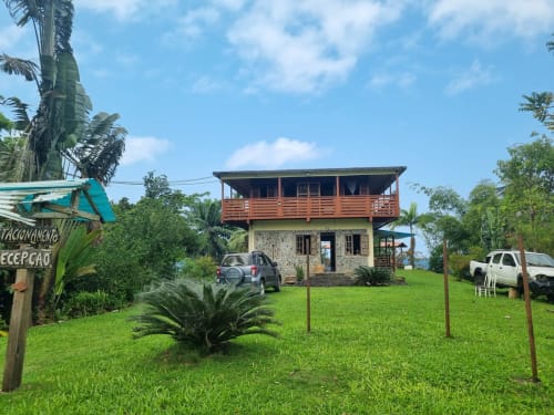 Casa elevada de madeira com vista para o mar em São Tomé, Equador. Propriedade residencial cercada por jardins tropicais
