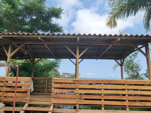 Pérgola de madeira com cobertura galvanizada na Equador Houses Vila Paraíso em São Tomé, com vista para jardim tropical e mar