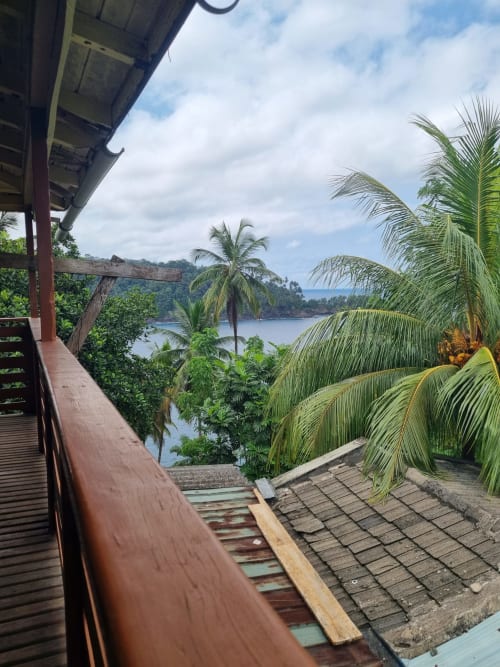 Varanda à beira-mar na Equador Houses, São Tomé, com palmeiras e vista para o mar da baía