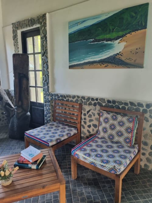Quarto costeiro nas Equador Houses, São Tomé com cadeiras de madeira, almofadas estampadas, pintura de praia e acesso à vista do mar