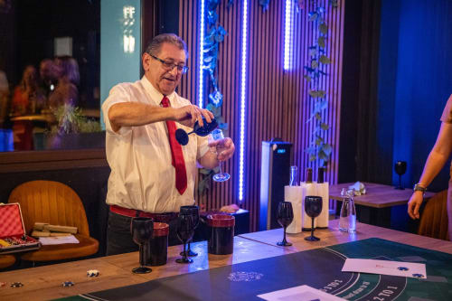 Man pouring wine at Hôtel Restaurant Le S'Y bar in Seingbouse with neon lighting and gaming table