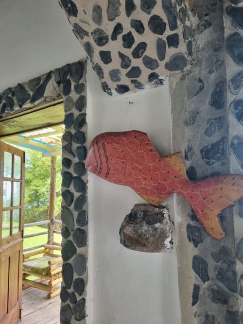 Quarto duplo da Vila Paraíso com paredes estampadas decorativas, tecido vermelho na parede e porta aberta revelando jardim com vista para o mar
