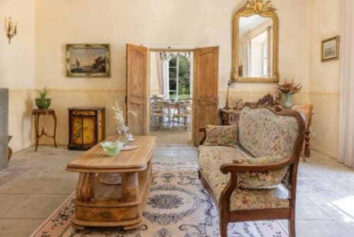 Élégant salon du gîte Château de Sienne à Chusclan avec mobilier d'époque, cheminée et portes-fenêtres ouvrant sur