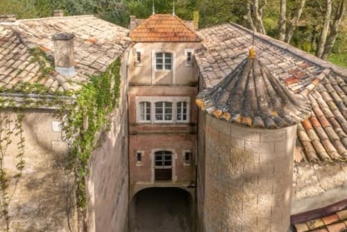 Vue aérienne de la tour historique du Château De Sienne avec toits en terre cuite, entourée de forêts à Chusclan