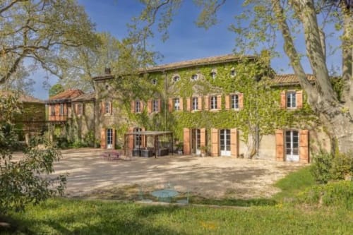 Château de Sienne, gîte à Chusclan avec bâtiments en terre cuite couverts de lierre, cour et grands arbres