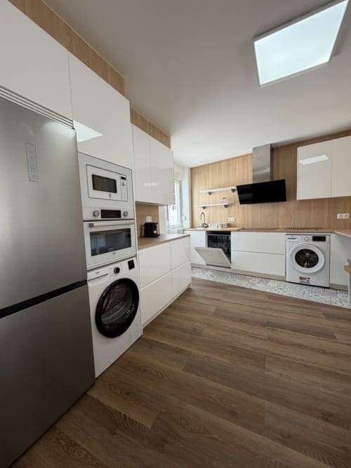 Cocina moderna en Bahia de Santoña con gabinetes blancos, electrodomésticos de acero inoxidable, acentos de madera y tragaluz