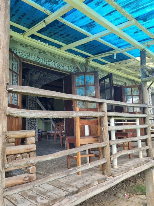 Chalé de madeira com telhado de metal azul em Equador Houses, São Tomé, com varandas rústicas e design aberto