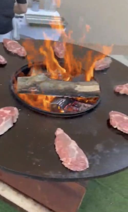 Flaming tableside cooking presentation at Hôtel Restaurant Le S'Y with meat and dramatic flames on dark surface