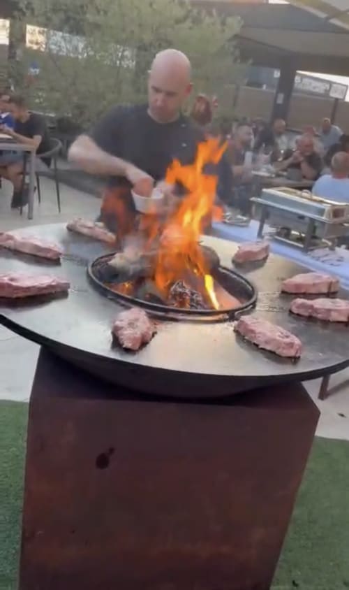 Chef grilling steaks over flames at Le S'Y hotel restaurant in Seingbouse, outdoor dining experience