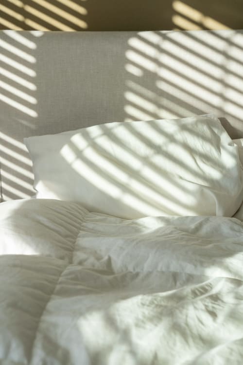 Lit baigné de soleil avec oreillers et draps blancs à l'hôtel L'escapade au Mans, France