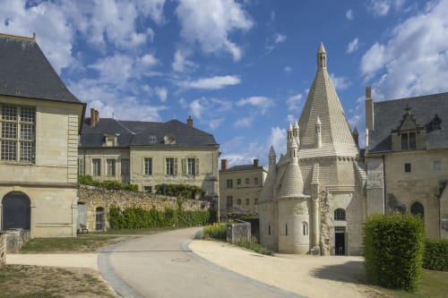 Chateau Haute Roche courtyard in Oudon, France with historic stone buildings and chapel tower under blue sky