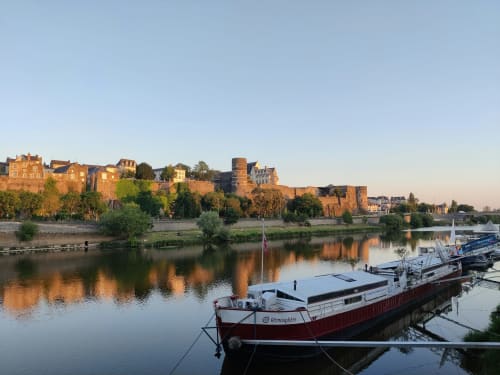 Chateau Haute Roche overlooking the Loire River in Oudon, France, with moored boats at sunset