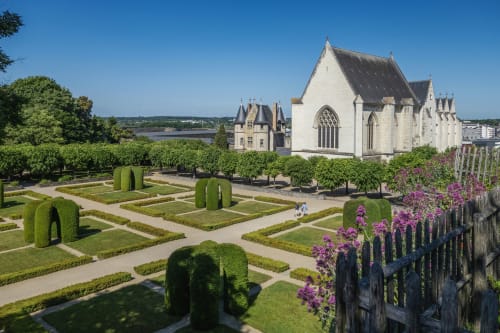 Château Haute Roche in Oudon, France with formal gardens, manicured hedges, and purple flowers overlooking the Loire Valley
