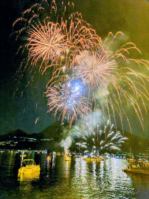 Fireworks burst over Lake Como at Villa Vista Lago di Como, Bellano, with boats and spectators enjoying the waterfront