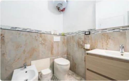 Bagno moderno nella camera Yaki Domo Silver, Cagliari. Completo di bidet, wc, lavabo, vasca e rivestimenti in piastrelle.