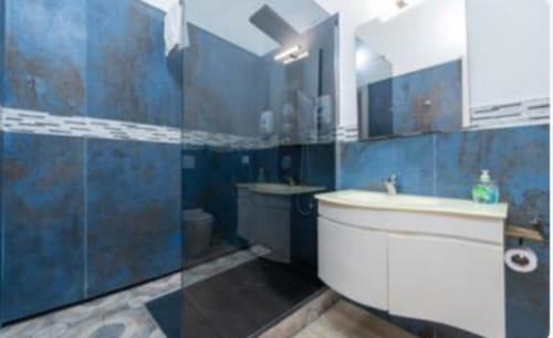 Bagno moderno presso il Yaki Domo B&B di Cagliari con piastrelle blu, lavabo bianco, WC e box doccia