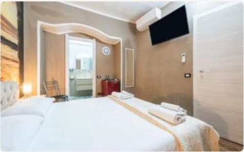 Camera moderna presso Yaki Domo Cagliari con letto bianco, TV a schermo piatto e bagno privato