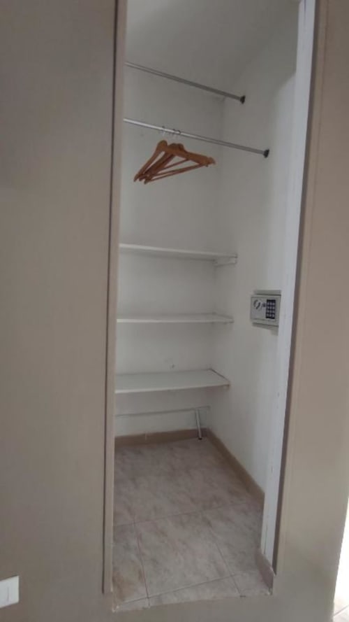 Cabina armadio con scaffalature bianche, aste metalliche, appendiabiti in legno e cassaforte elettronica nella Gold room dello Yaki Domo B&B, Cagliari