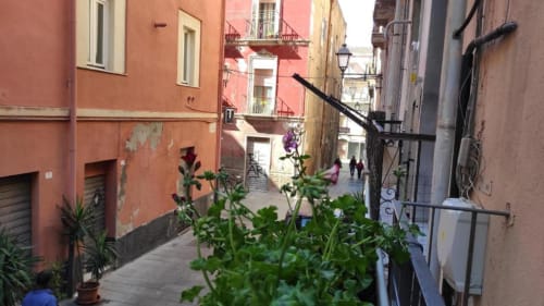 Affascinante vicoletto a Cagliari con edifici colorati e piante in vaso, vista dal balcone di Yaki Domo
