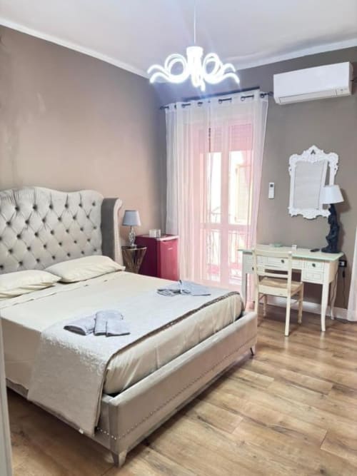 Camera Platinum dello Yaki Domo Cagliari B&B con letto trapuntato color crema, luce al neon, tende rosa e arredi moderni