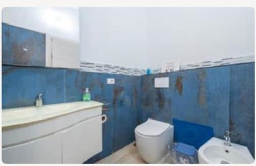 Bagno moderno nella suite Platinum di Yaki Domo a Cagliari con piastrelle blu, wc, bidet e lavabo bianchi