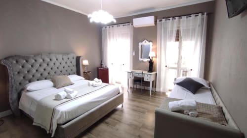 Ampia camera da letto allo Yaki Domo B&B di Cagliari con testata trapuntata, divano letto, toilette e finestre luminose