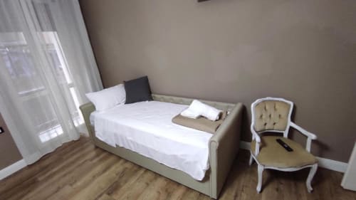 Camera Platinum presso Yaki Domo B&B a Cagliari con letto matrimoniale, biancheria bianca, elegante poltrona, pavimento in legno e accesso al balcone