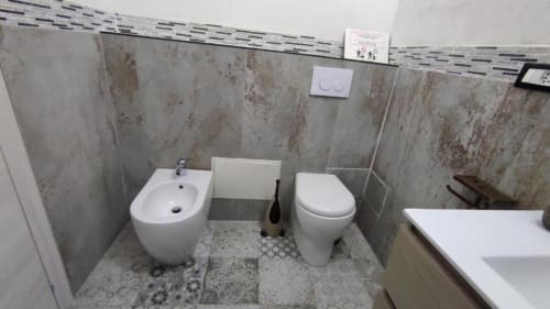 Bagno moderno nella camera Yaki Domo Silver, Cagliari, con bidet, WC, piastrelle rigate e pavimento a motivi decorativi.