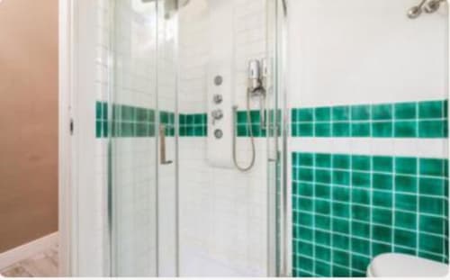 Bagno moderno della suite Yaki Domo Gold a Cagliari con doccia a piastrelle verdi e pareti bianche