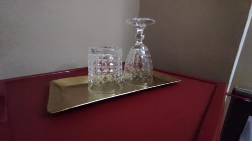 Due bicchieri di cristallo con motivi decorativi su un vassoio dorato nella Silver room del Yaki Domo B&B di Cagliari